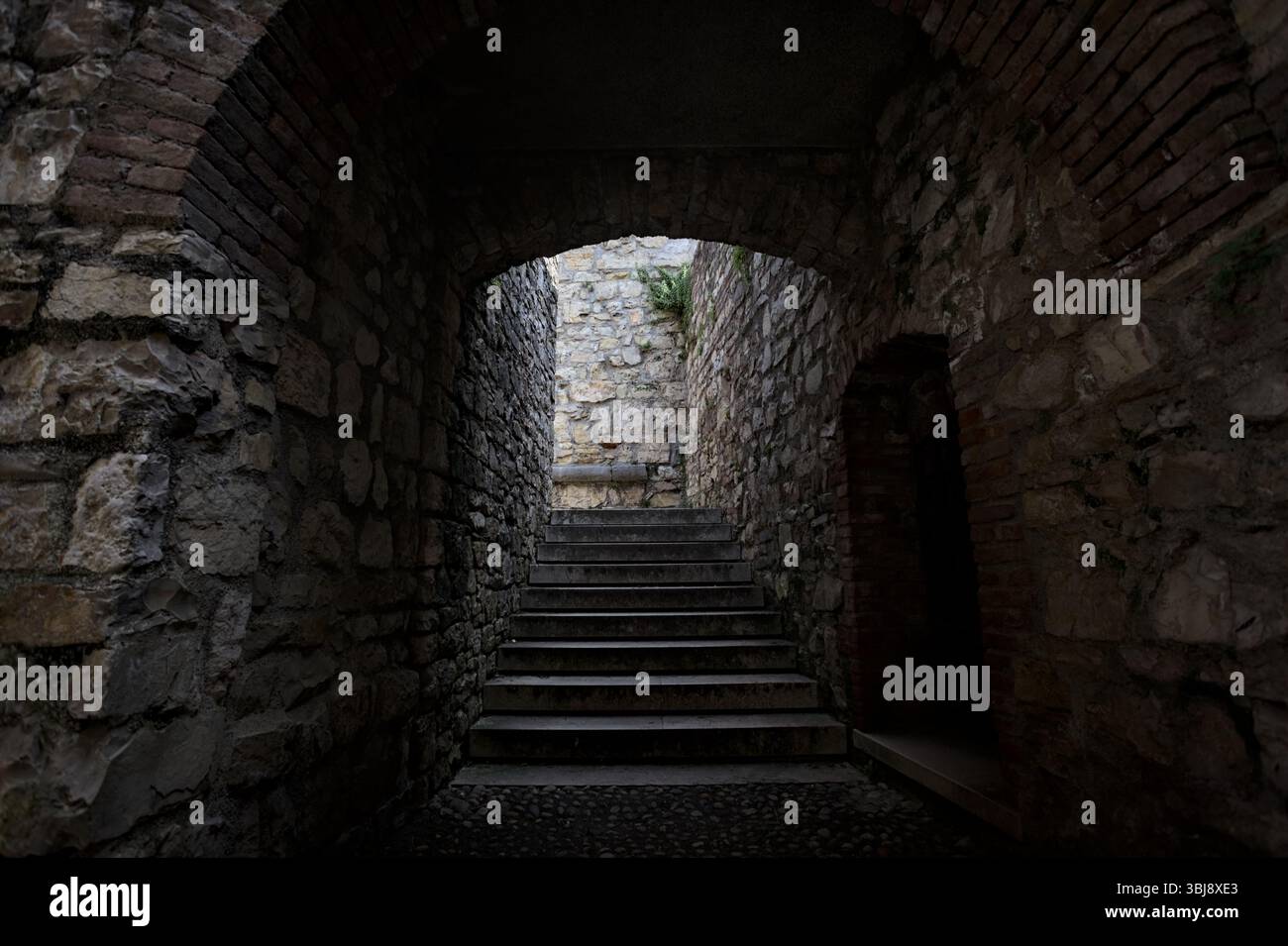 Scala in pietra all'ombra che passa sotto un arco Foto Stock