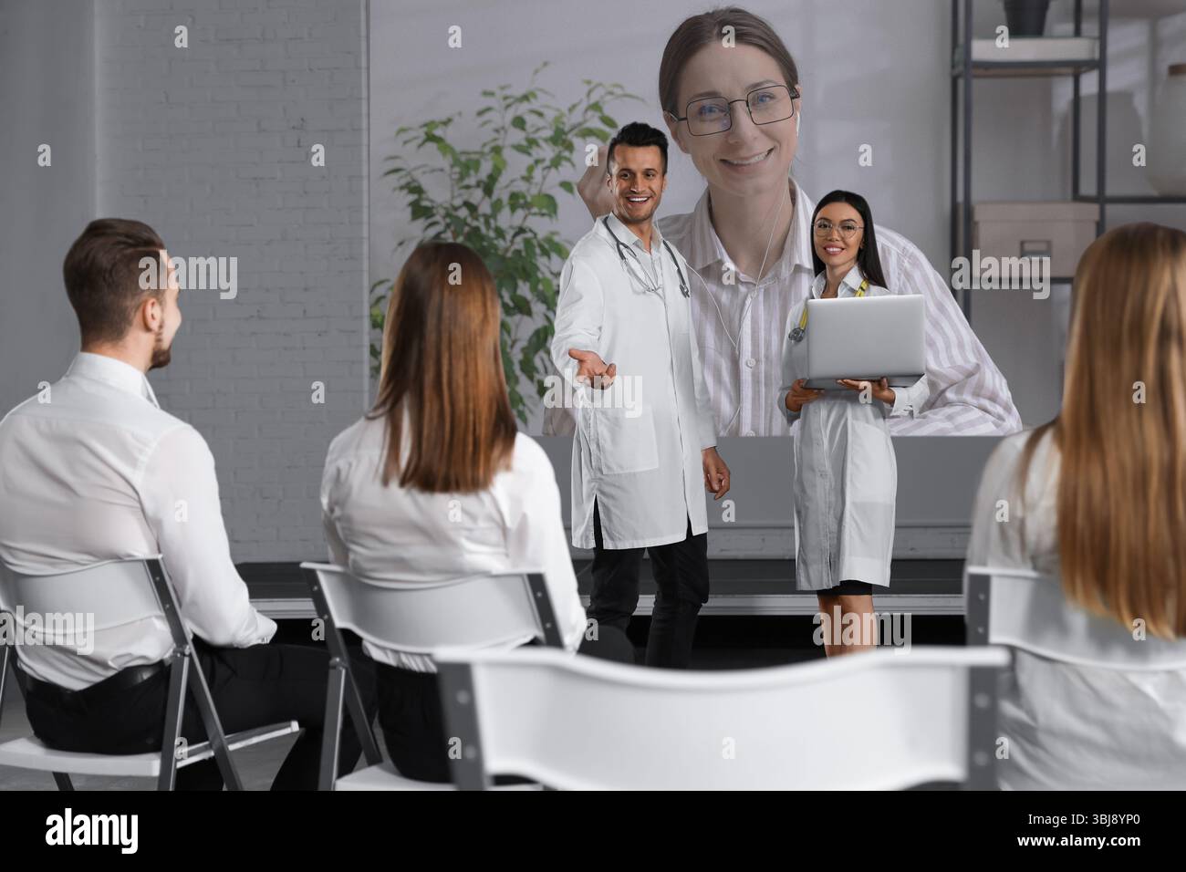 Team di medici che utilizzano il videoproiettore durante le conferenze al chiuso. Altoparlante sullo schermo di proiezione Foto Stock