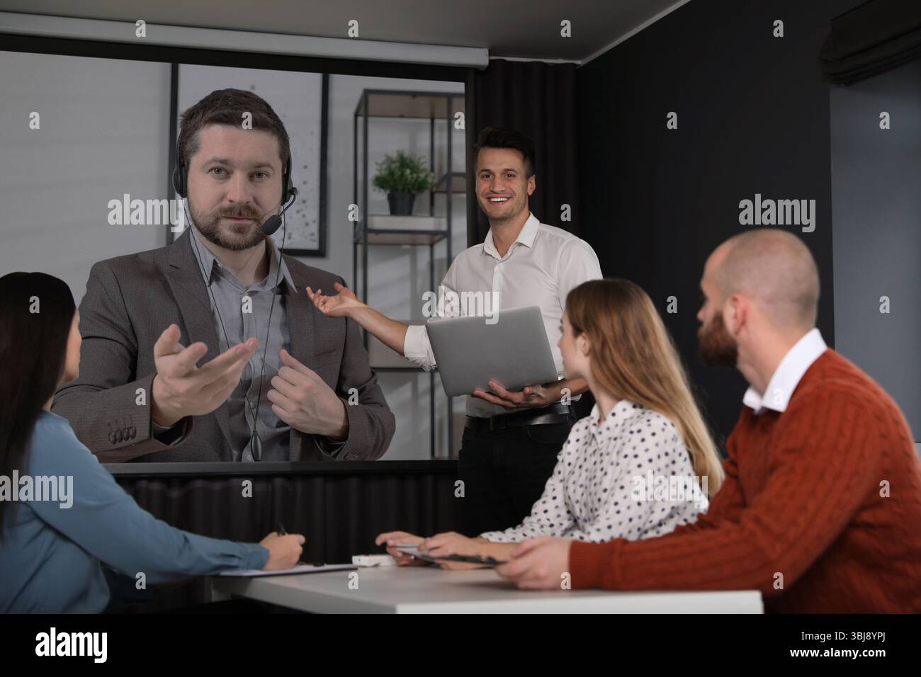 Gruppo di persone che partecipano a una conferenza aziendale al chiuso. Altoparlante sullo schermo di proiezione Foto Stock