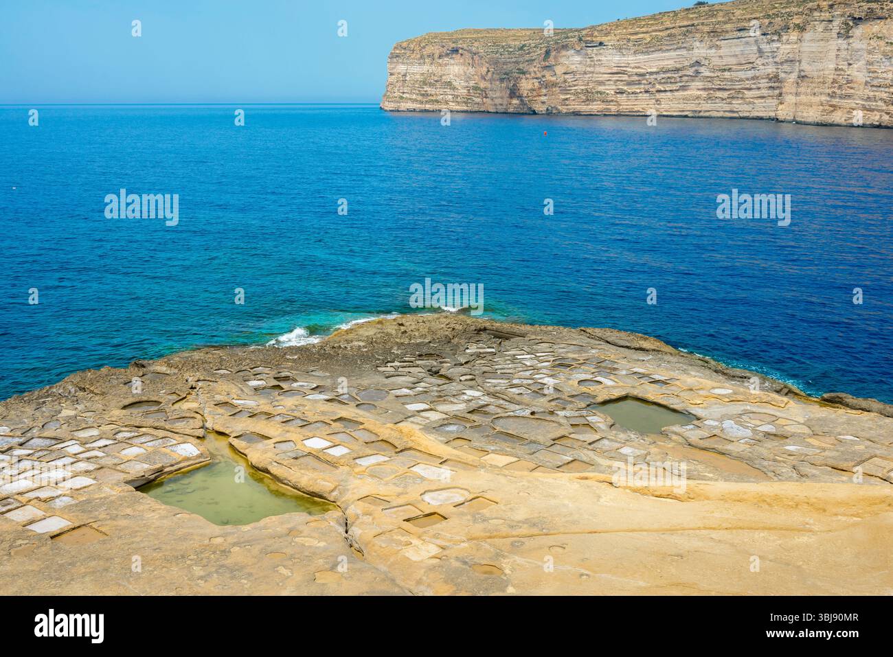Costa di Gozo Malta, vista delle antiche saline tagliate in cima al promontorio all'ingresso della baia di Xlendi, costa meridionale dell'isola di Gozo, Malta Foto Stock