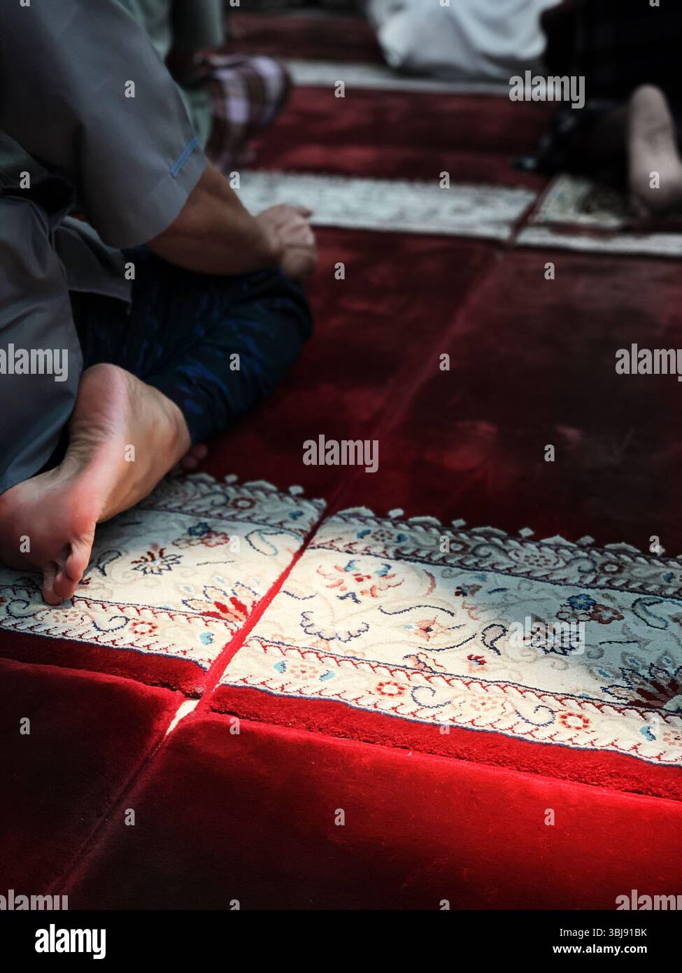 Adoratore inginocchiato sul tappeto di preghiera rosso. - Immagine stock catturata con smartphone