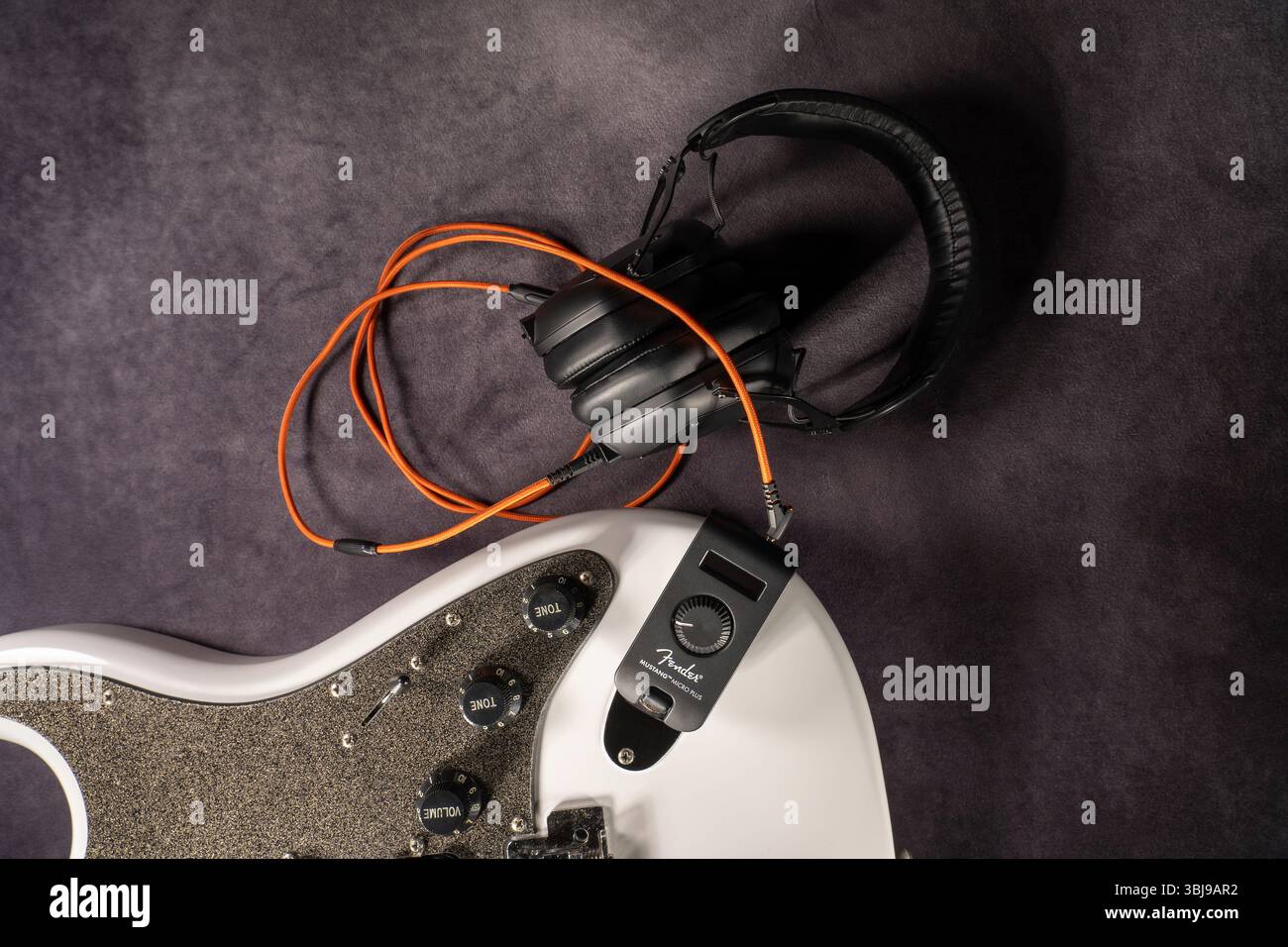 Cuffie per chitarra AMP Fender Mustang Micro Plus con una chitarra elettrica bianca sullo sfondo. Foto scattata il 9 aprile 2025 in Spagna. Foto Stock