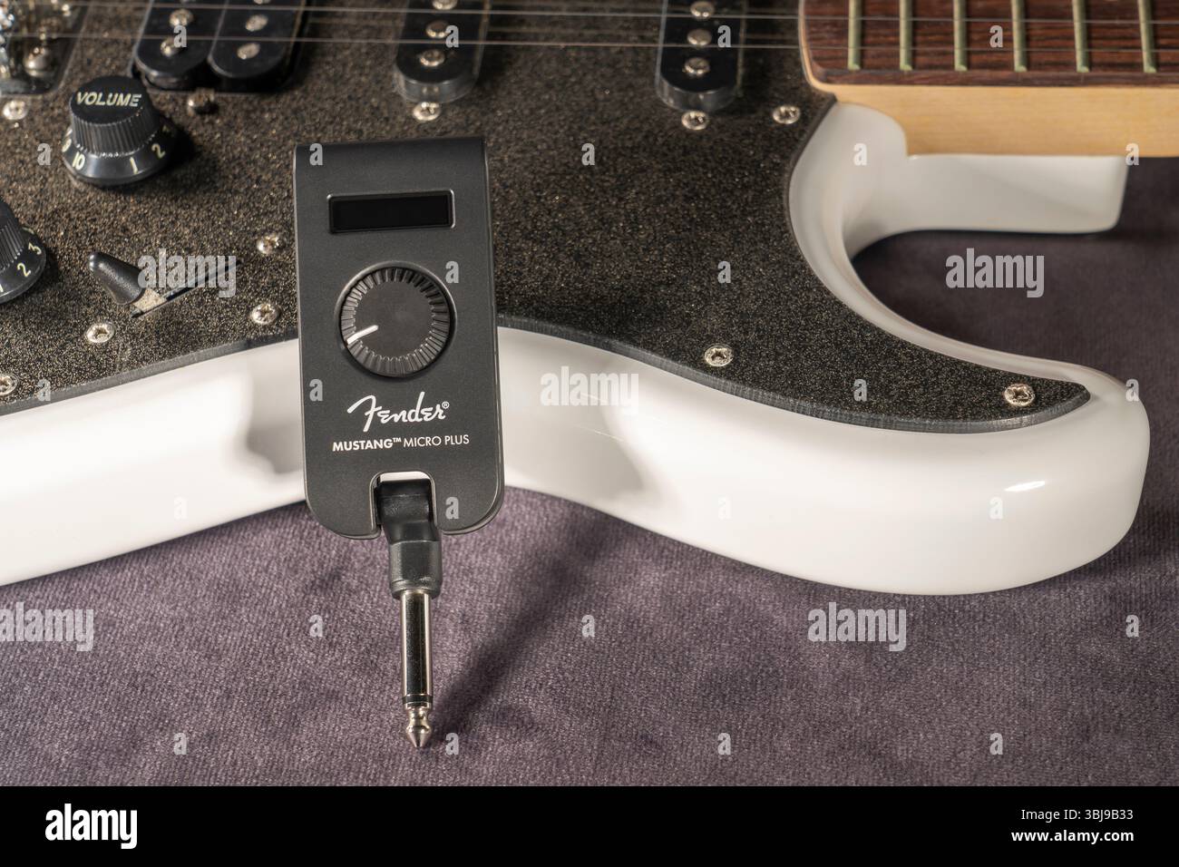 Cuffie per chitarra AMP Fender Mustang Micro Plus con una chitarra elettrica bianca sullo sfondo. Foto scattata il 9 aprile 2025 in Spagna. Foto Stock