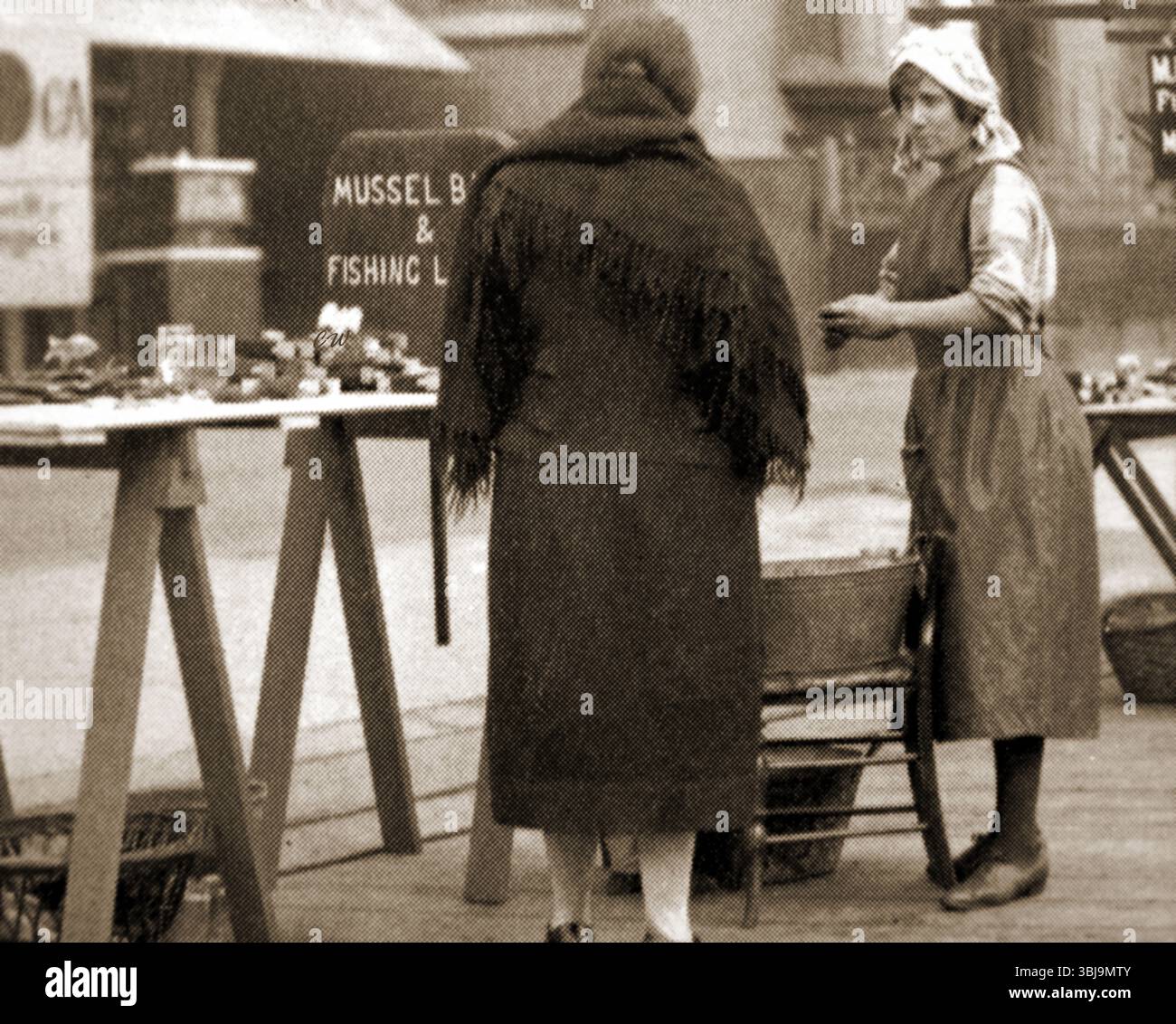 Whitby Yorkshire in passato - le mogli di pescatori vendono pesce e lenze da pesca, pesi da pesca, esche di cozze, ecc. dalle bancarelle a lato della strada sul molo per integrare il loro reddito Foto Stock