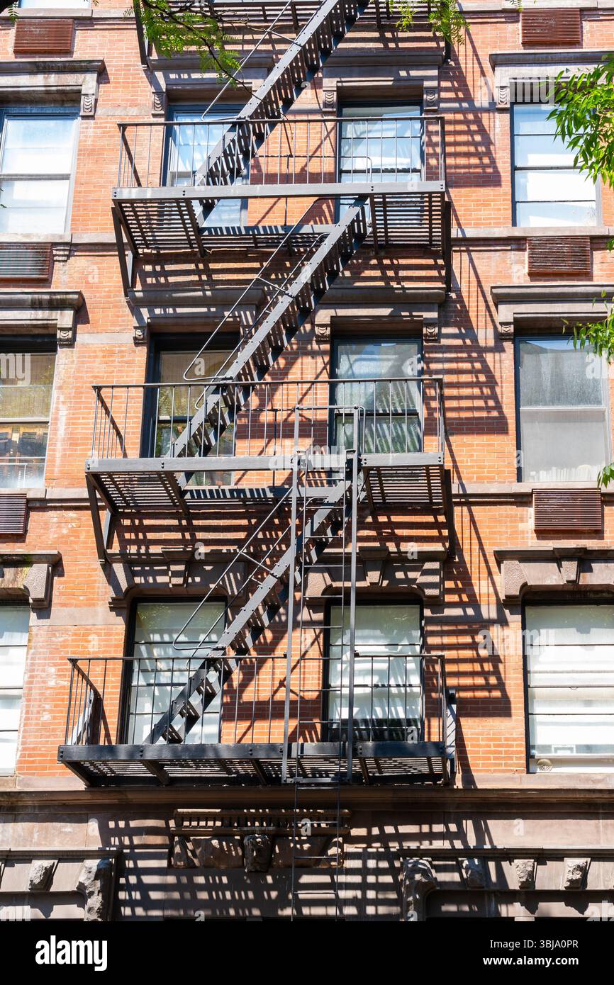 Un vecchio edificio di appartamenti in mattoni rossi con scale antincendio. New York, Stati Uniti Foto Stock