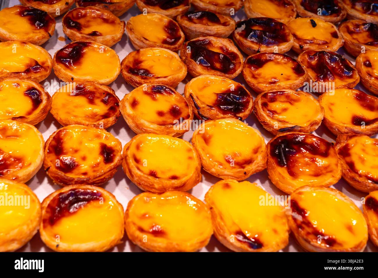Tradizionali crostate portoghesi alla crema pasticcera (pastel de nata) appena sfornate in un negozio in vendita. Foto Stock