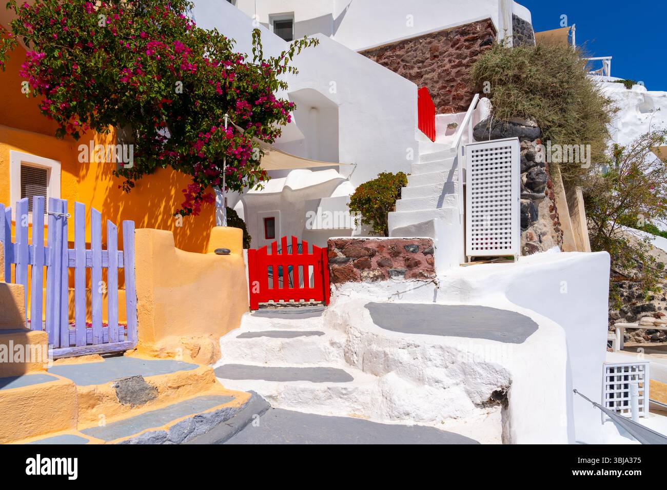 Pareti colorate e cancello con edifici bianchi a Oia, l'isola di Santorini. Foto Stock