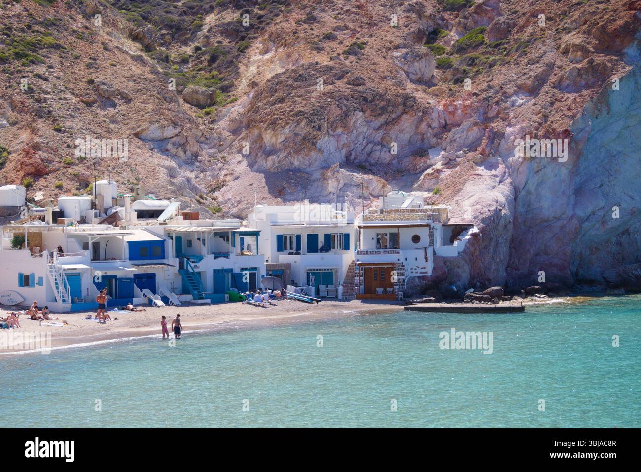 Spiaggia di Firopotamos sull'isola di Milos con mare turchese, tradizionali capanne da pesca e luminose scogliere di zolfo marmorizzate sotto un cielo limpido. Foto Stock