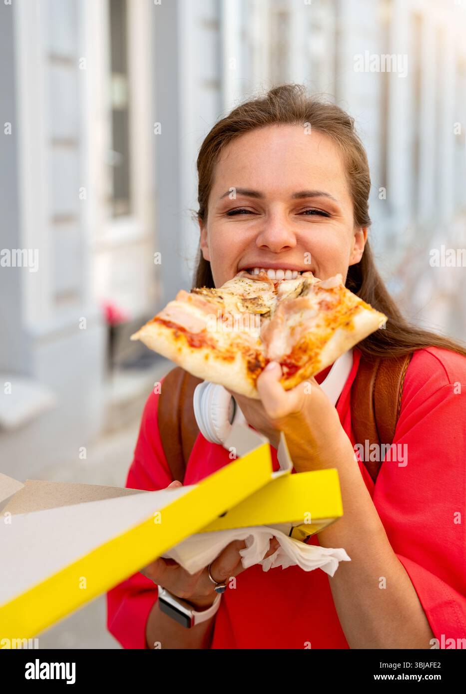 Giovane donna che si diverte con la pizza da asporto in città Foto Stock