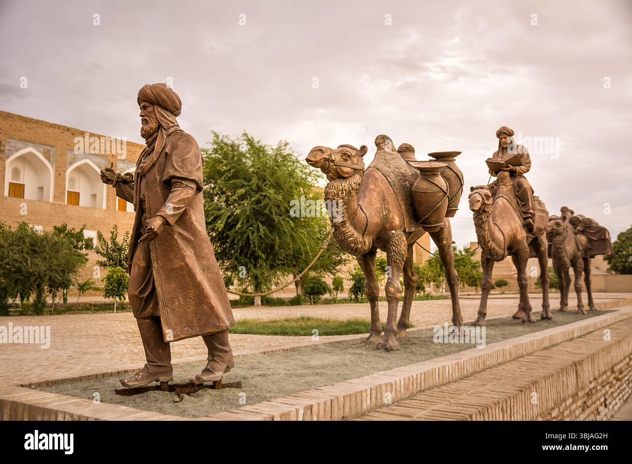 Khiva, Uzbekistan - 11 luglio 2024: Installazione di scultura in bronzo che rappresenta un caravanserraglio, con cammelli e una guida - commemorazione dell'antico commercio ro Foto Stock