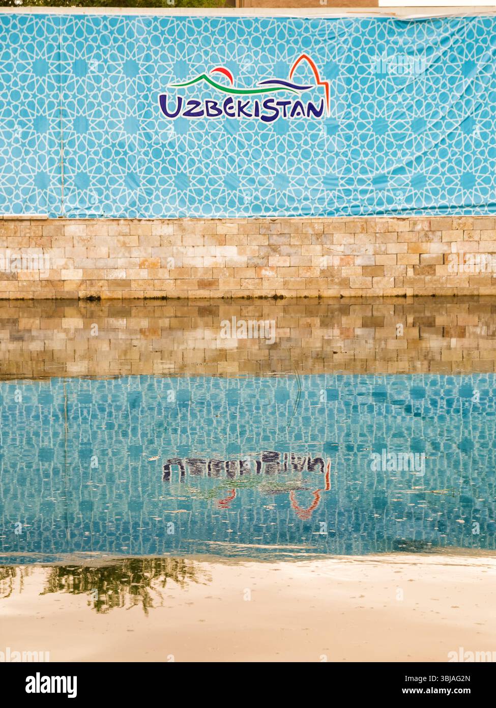 Khiva, Uzbekistan - 11 luglio 2024: L'emblema nazionale dell'Uzbekistan si riflette in una piscina, che rappresenta l'identità statale e l'orgoglio culturale. Foto Stock