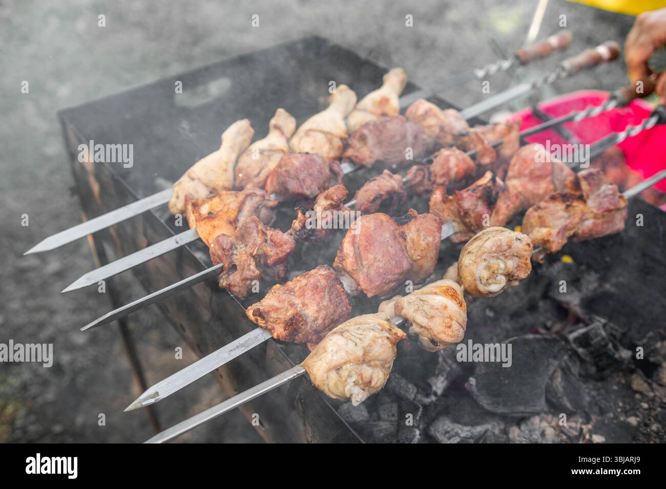 Godetevi un vivace raduno all'aperto mentre gli spiedini di carne marinata cucinano sopra il carbone scintillante in un'invitante atmosfera da cortile Foto Stock