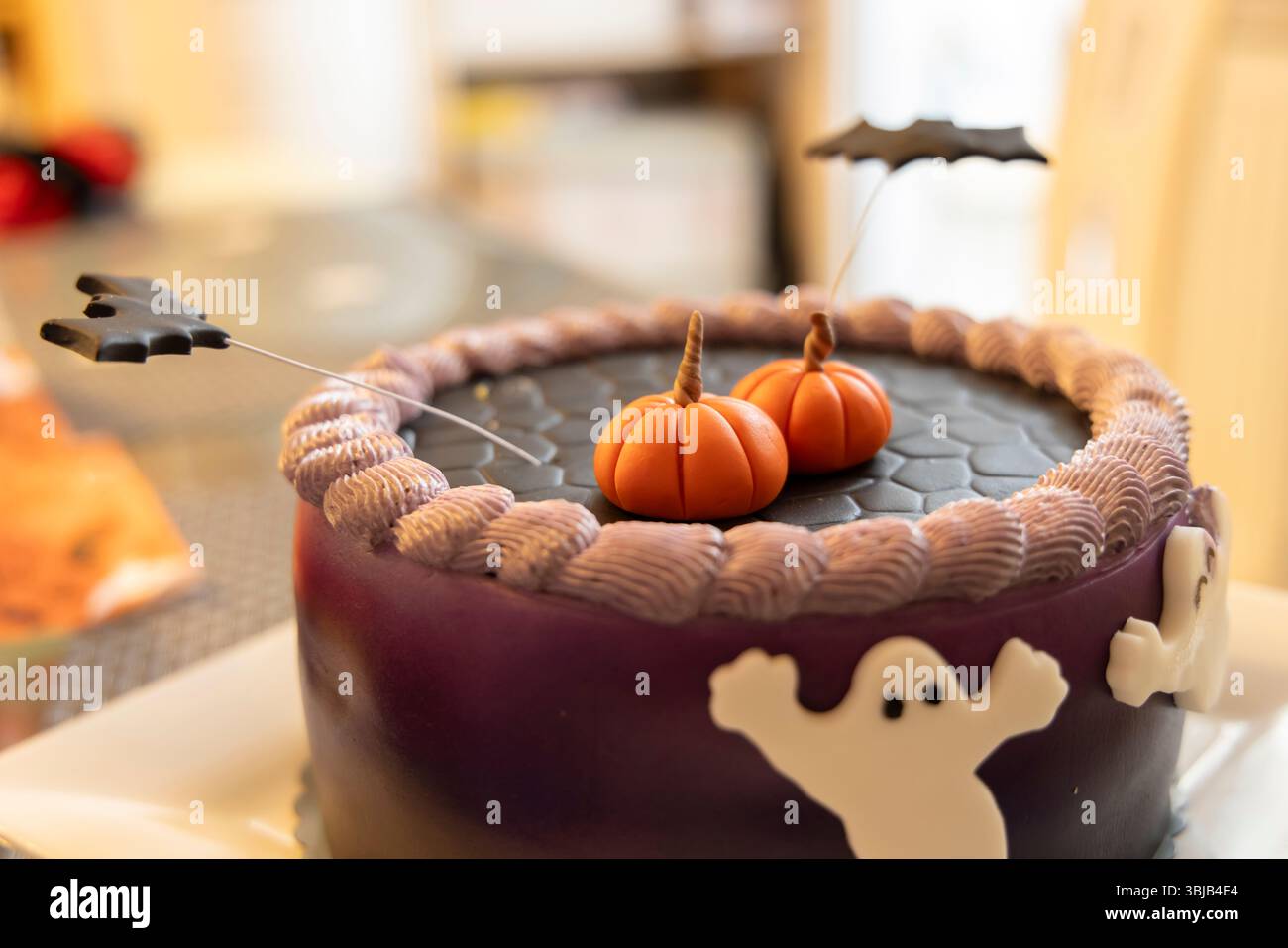 Torta di halloween rotonda con glassa viola, zucche fondenti, pipistrelli e decorazioni fantasmi Foto Stock