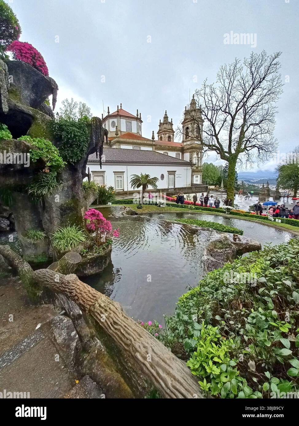 Braga Portogallo marzo 29 2024 stagno con giardini lussureggianti e vista sulle torri del santuario di Bom Jesus do Monte con i visitatori che camminano nelle vicinanze Foto Stock