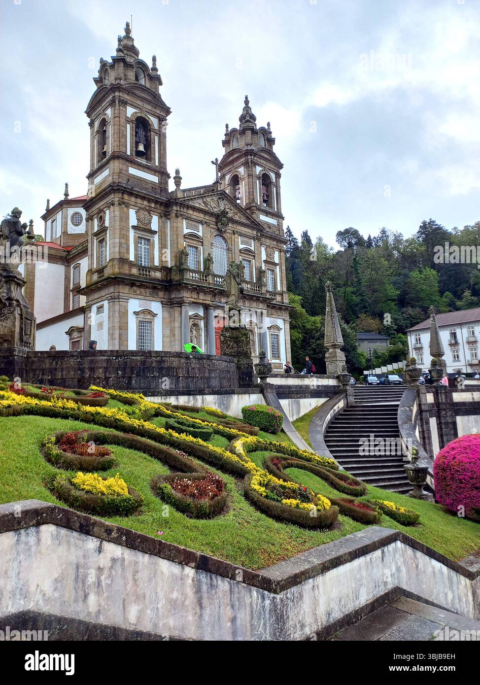 Braga Portogallo marzo 29 2024 chiesa barocca di Bom Jesus do Monte con i visitatori che scalano scale e aiuole in primo piano Foto Stock