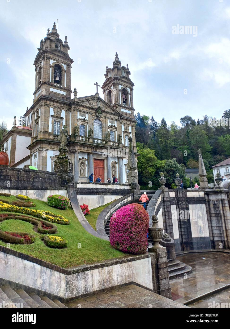 Braga Portogallo marzo 29 2024 chiesa barocca di Bom Jesus do Monte con i visitatori che scalano scale e aiuole in primo piano Foto Stock