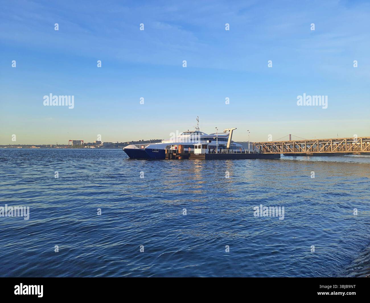 Lisbona, Portogallo. 12 aprile 2024 traghetto blu e bianco per pendolari ormeggiato al molo di Cais do Sodré a Lisbona, con le calme acque del fiume Tago che riflettono un Foto Stock