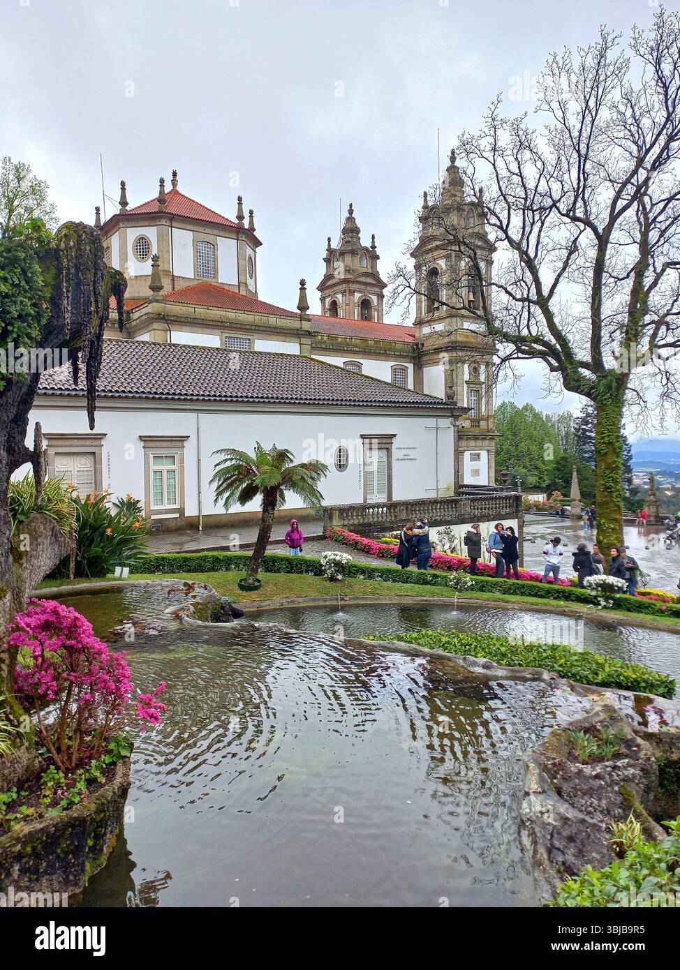 Braga Portogallo marzo 29 2024 stagno con giardini lussureggianti e vista sulle torri del santuario di Bom Jesus do Monte con i visitatori che camminano nelle vicinanze Foto Stock