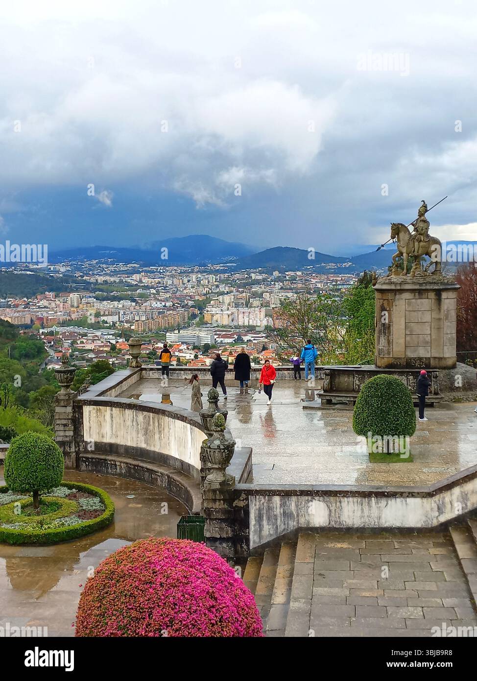 Braga Portogallo marzo 29 2024 i visitatori ammirano la vista panoramica di Braga dalla terrazza in pietra con statua equestre e cielo nuvoloso a Bom Jesus do Monte Foto Stock