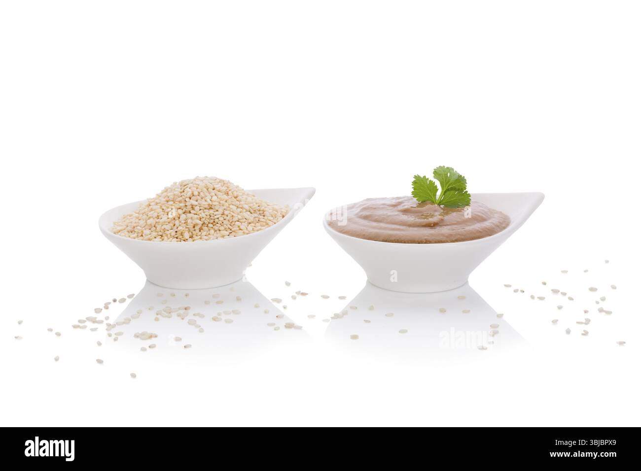 Bagno di tahini e semi di sesamo in ciotole bianche isolate su sfondo bianco. Cucina tradizionale africana e mediorientale Foto Stock