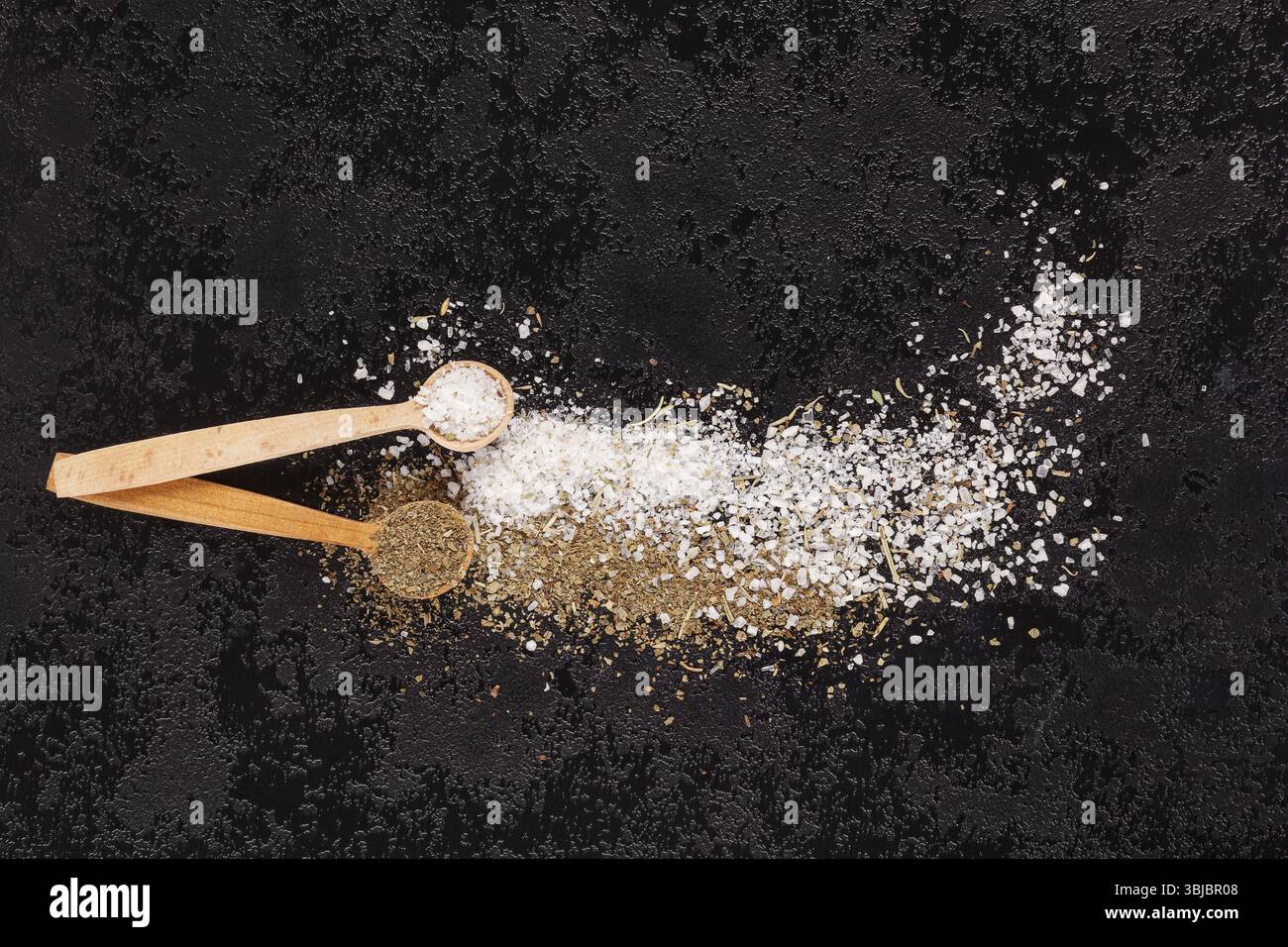 Background culinario. Sale marino con erbe secche su sfondo nero Foto Stock