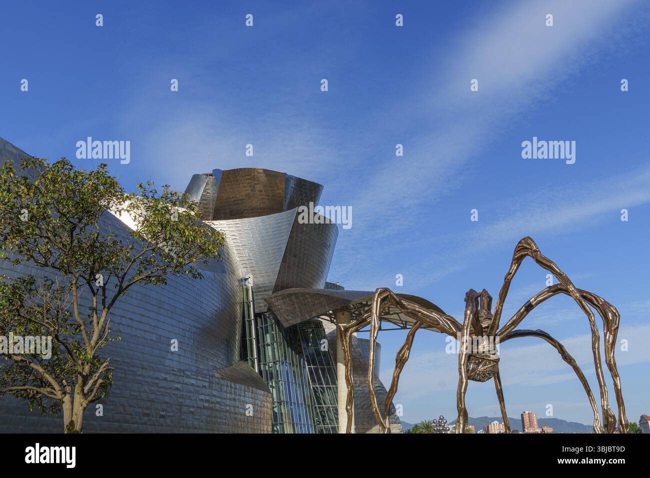 Scultura metallica del ragno accanto a un edificio moderno sotto il cielo blu, Bilbao, Paesi Baschi, Spagna, Europa Foto Stock
