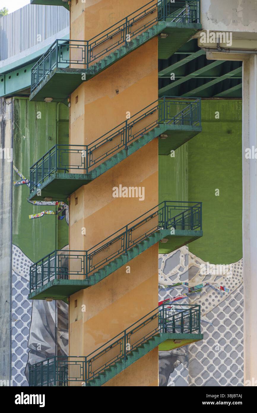 Scala antincendio arancione con ringhiere verdi, montata su un edificio sotto un ponte, Bilbao, Paesi Baschi, Spagna, Europa Foto Stock