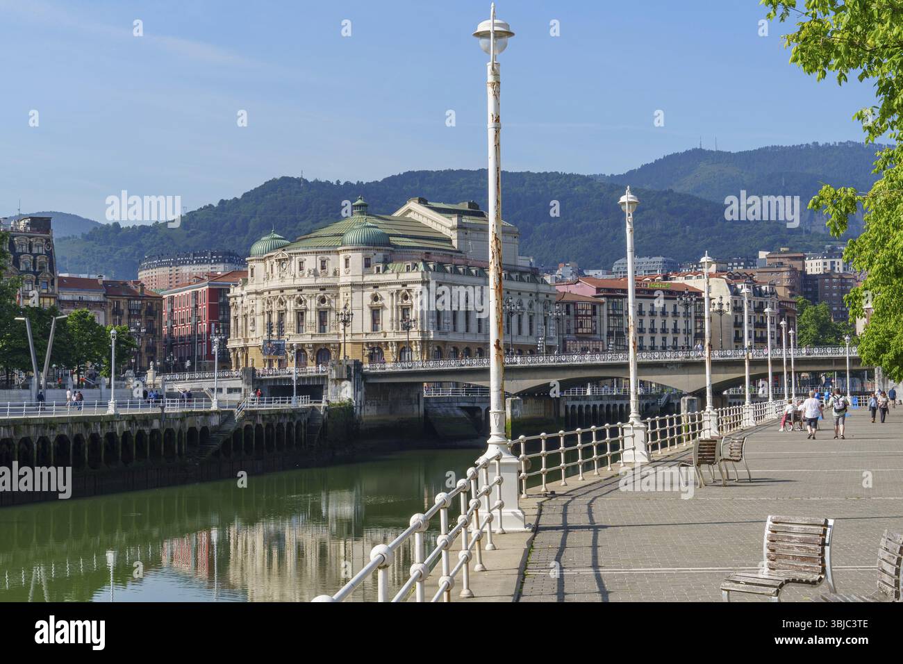 Passeggiata lungo un fiume con vista su un edificio storico e ponte, Bilbao, Paesi Baschi, Spagna, Europa Foto Stock