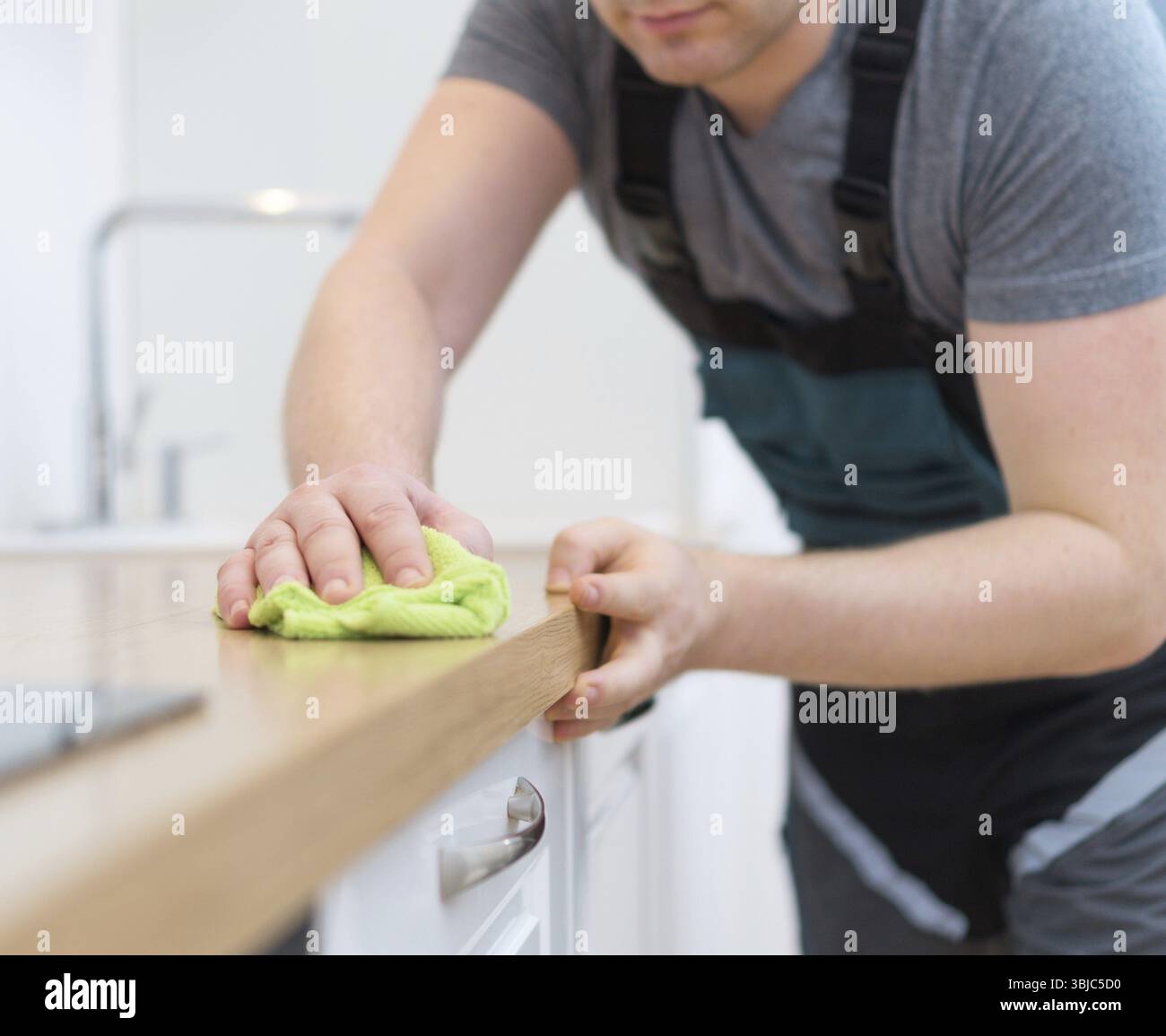 Concetto di servizio di pulizia. Uomo che pulisce mobili da cucina Foto Stock