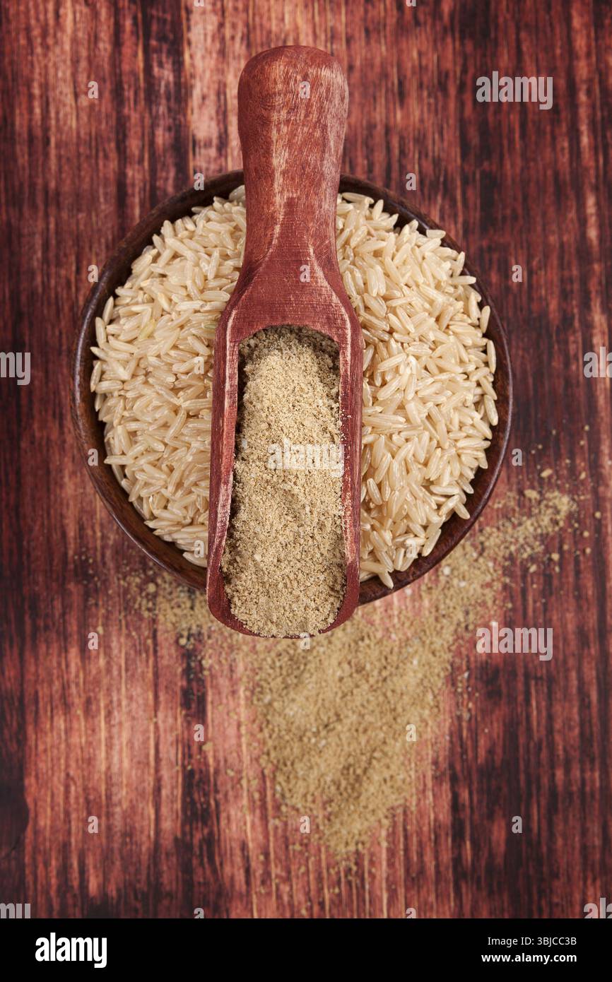 Fibra alimentare. Riso in una ciotola rotonda di legno con fibra di riso dietetica su fondo di legno marrone scuro, vista dall'alto. Concetto di alimentazione sana Foto Stock