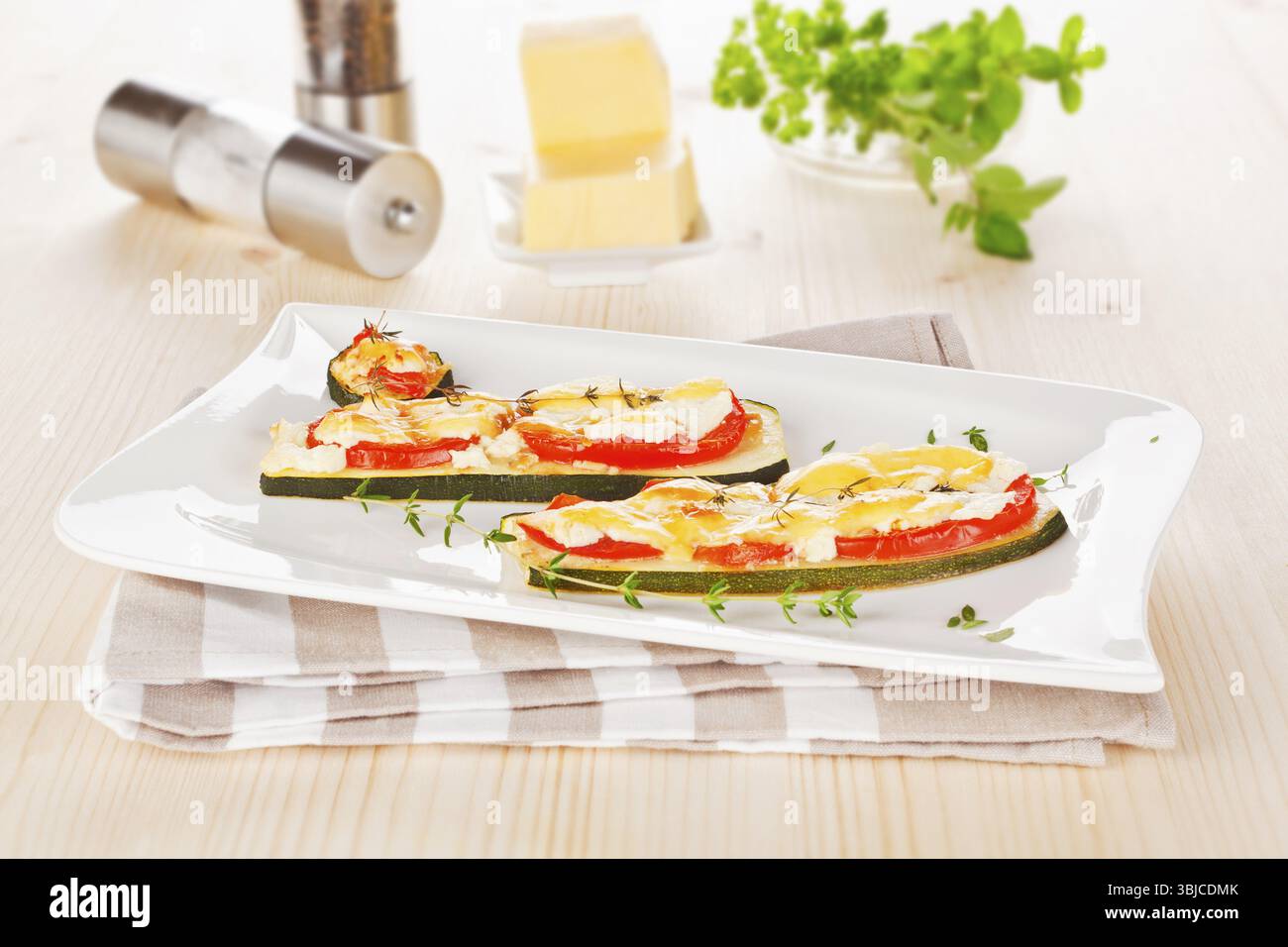 Lussuose fette di zucchine al forno con pomodoro e formaggio. Cucina vegetariana Foto Stock