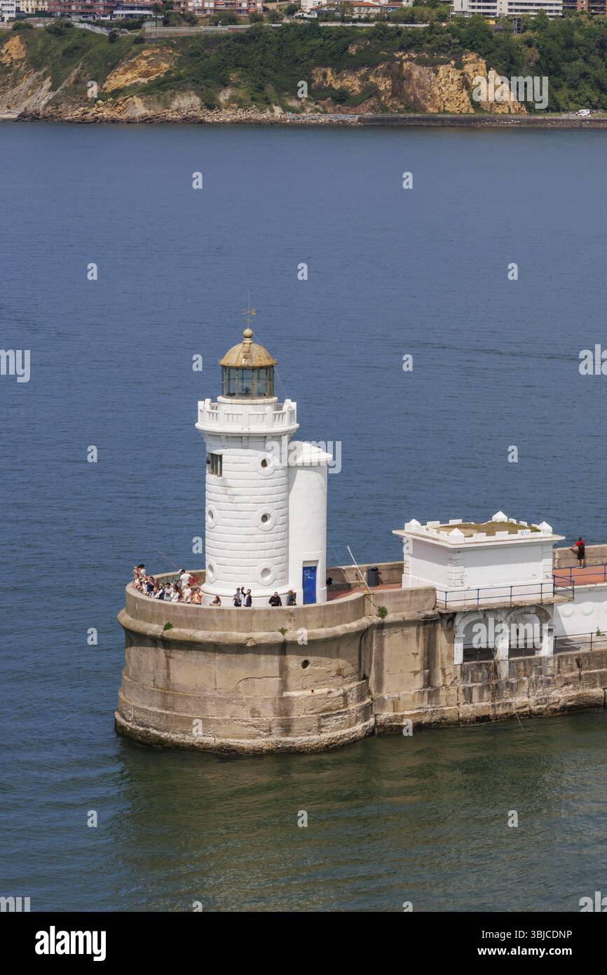 Faro bianco sulla costa con gente che gode la vista, Gexto, Paesi Baschi, Spagna, Europa Foto Stock