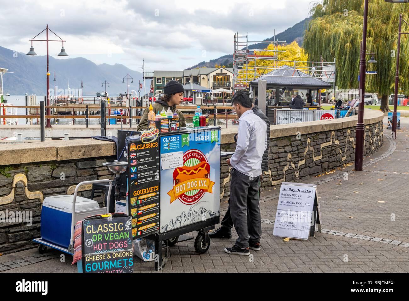 Venditrice di cibo di strada sulla passeggiata del molo di Queenstown che vende frankfurter, hot dog classici e hot dog vegani e bacon butty, regione di Otago, nuova Zelanda Foto Stock