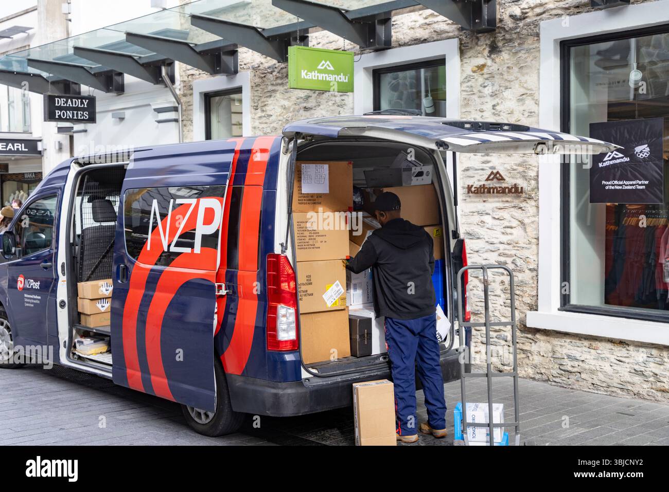 New Zealand Post, operatore postale che consegna le scatole al negozio di Kathmandu nel centro di Queenstown, nella regione di Otago, nell'isola meridionale, in nuova Zelanda Foto Stock