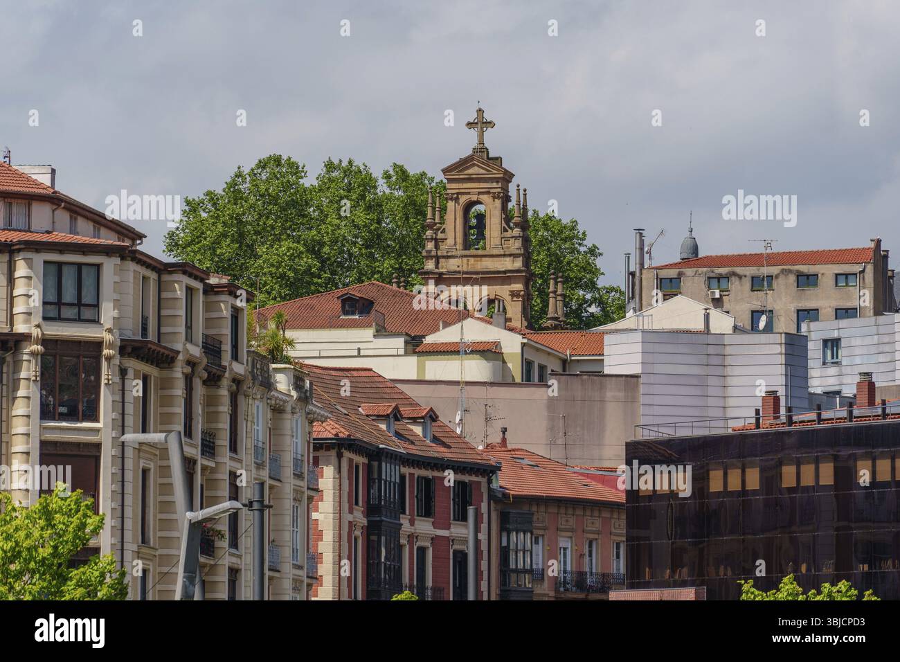 La chiesa storica si erge su edifici circostanti con alberi sullo sfondo, Bilbao, Paesi Baschi, Spagna, Europa Foto Stock