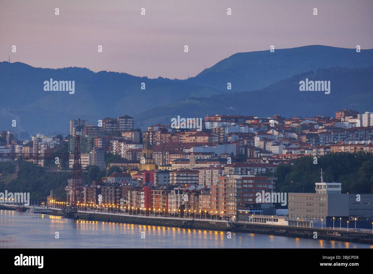 Vista serale della città con edifici illuminati sullo sfondo di una montagna, Gexto, Paesi Baschi, Spagna, Europa Foto Stock