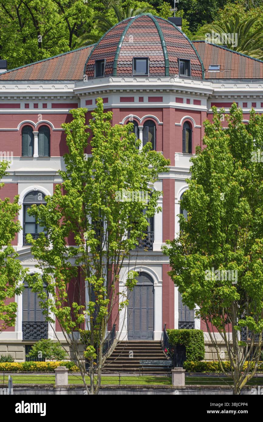 Un edificio storico rosso con una cupola circondata da alberi verdi, Bilbao, Paesi Baschi, Spagna, Europa Foto Stock