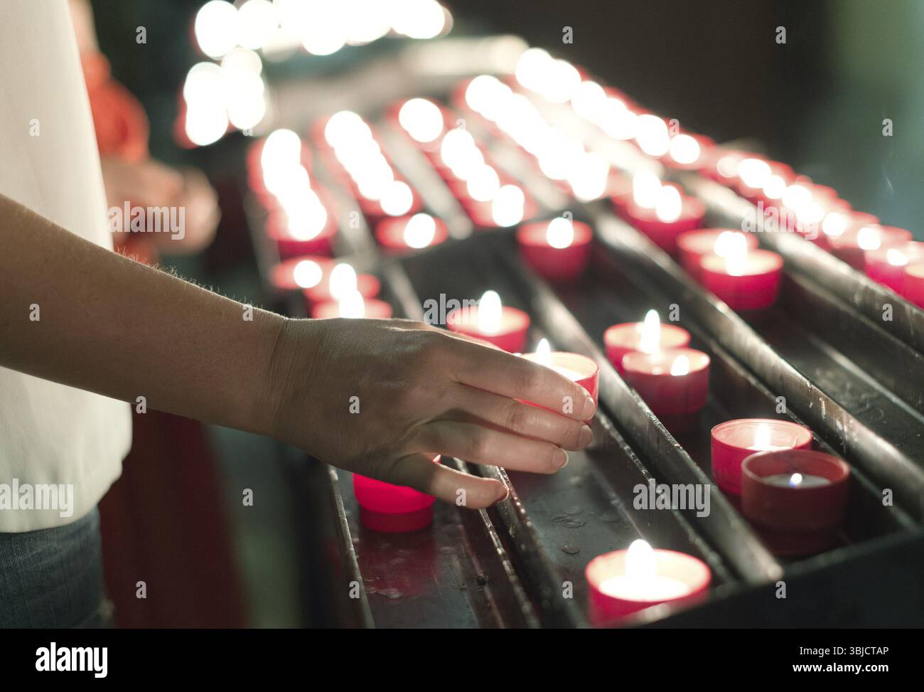 La donna mette una candela sull'altare in chiesa Foto Stock