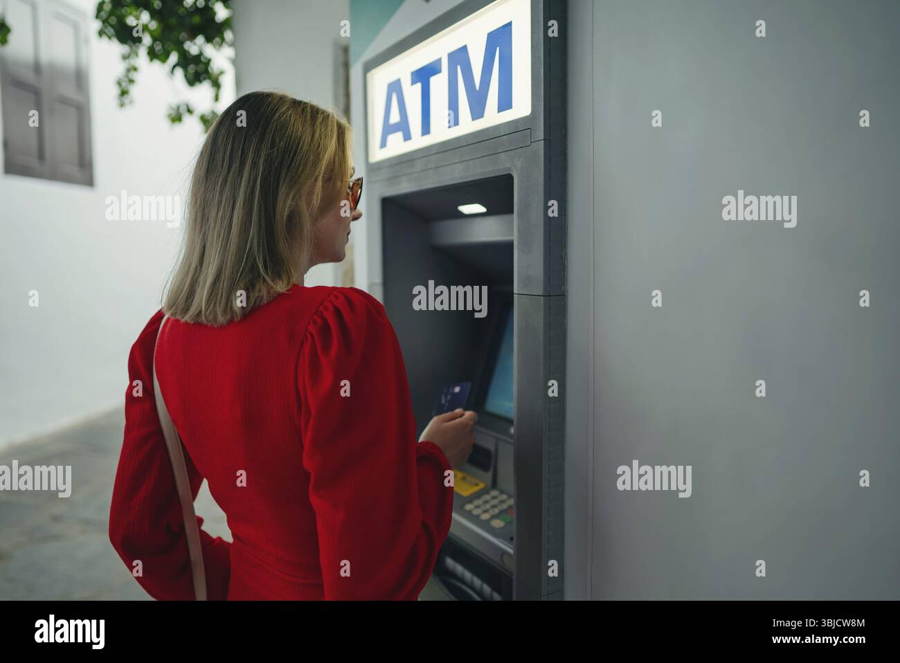 Donna che usa il bancomat per strada Foto Stock