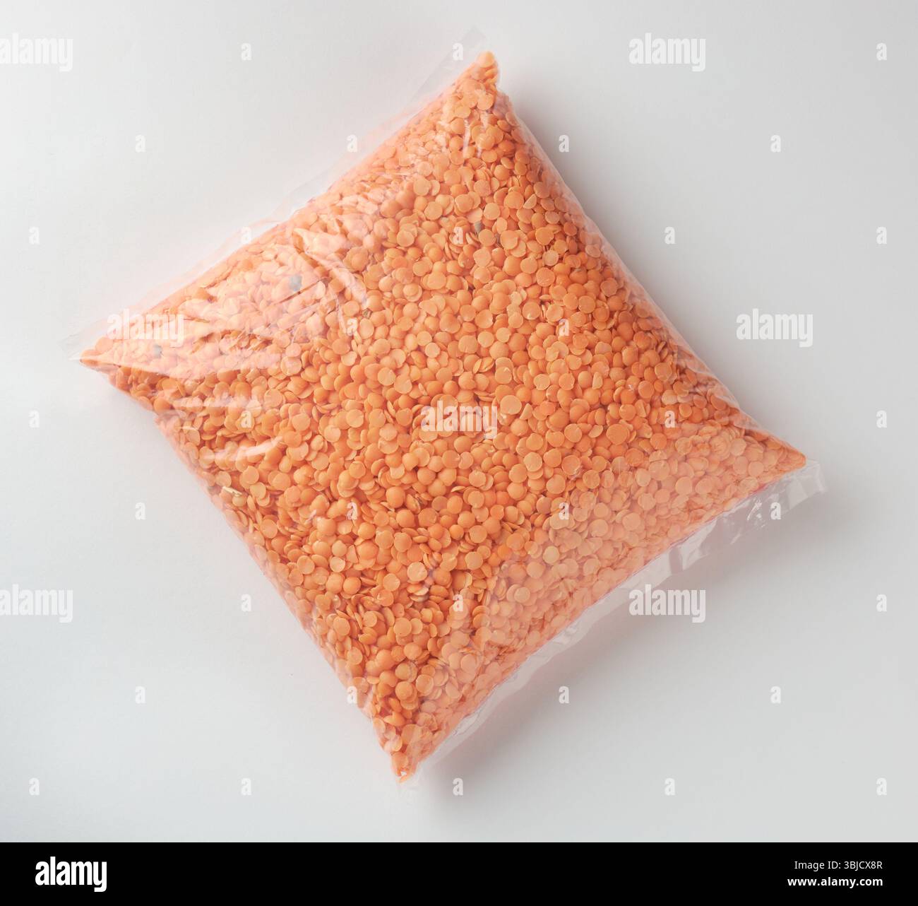 confezione trasparente di lenticchie rosse o masoor da sfondo bianco isolato, ingrediente da utilizzare per cucinare cucine indiane, mediorientali e sud-asiatiche Foto Stock