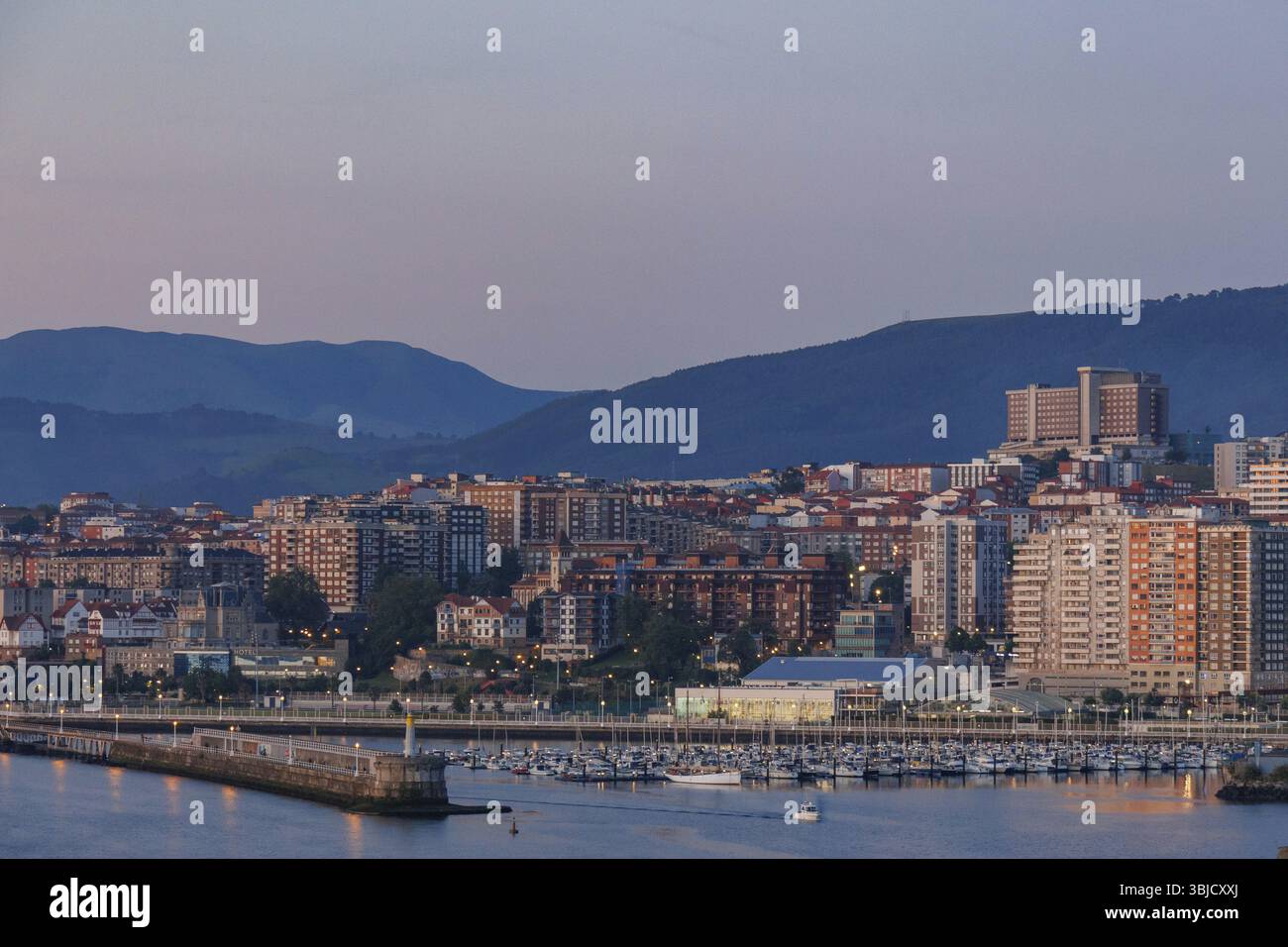 Silhouette urbana al crepuscolo con montagne sullo sfondo e edifici illuminati, Gexto, Paesi Baschi, Spagna, Europa Foto Stock