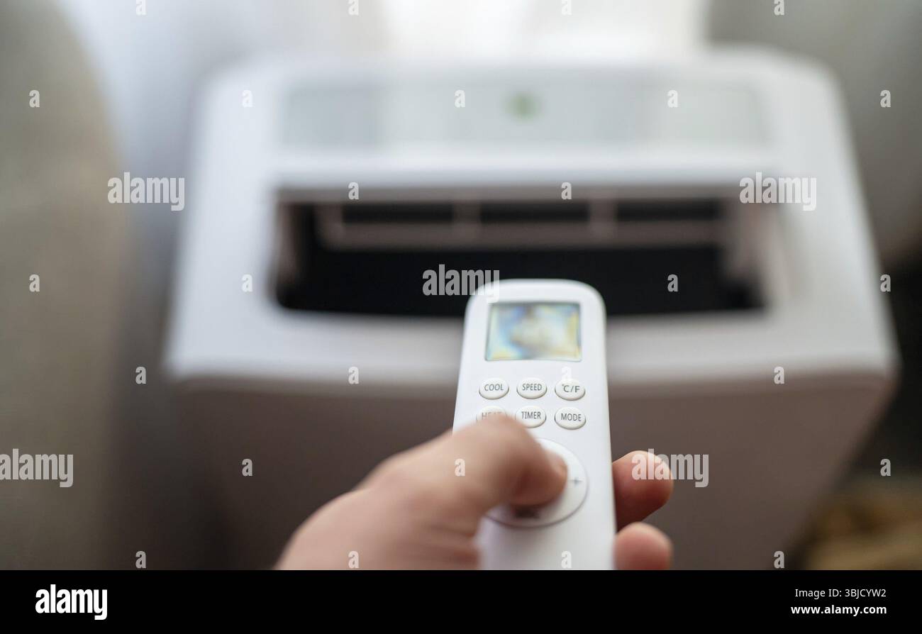 Telecomando con impugnatura rivolto verso il condizionatore d'aria mobile a pavimento Foto Stock