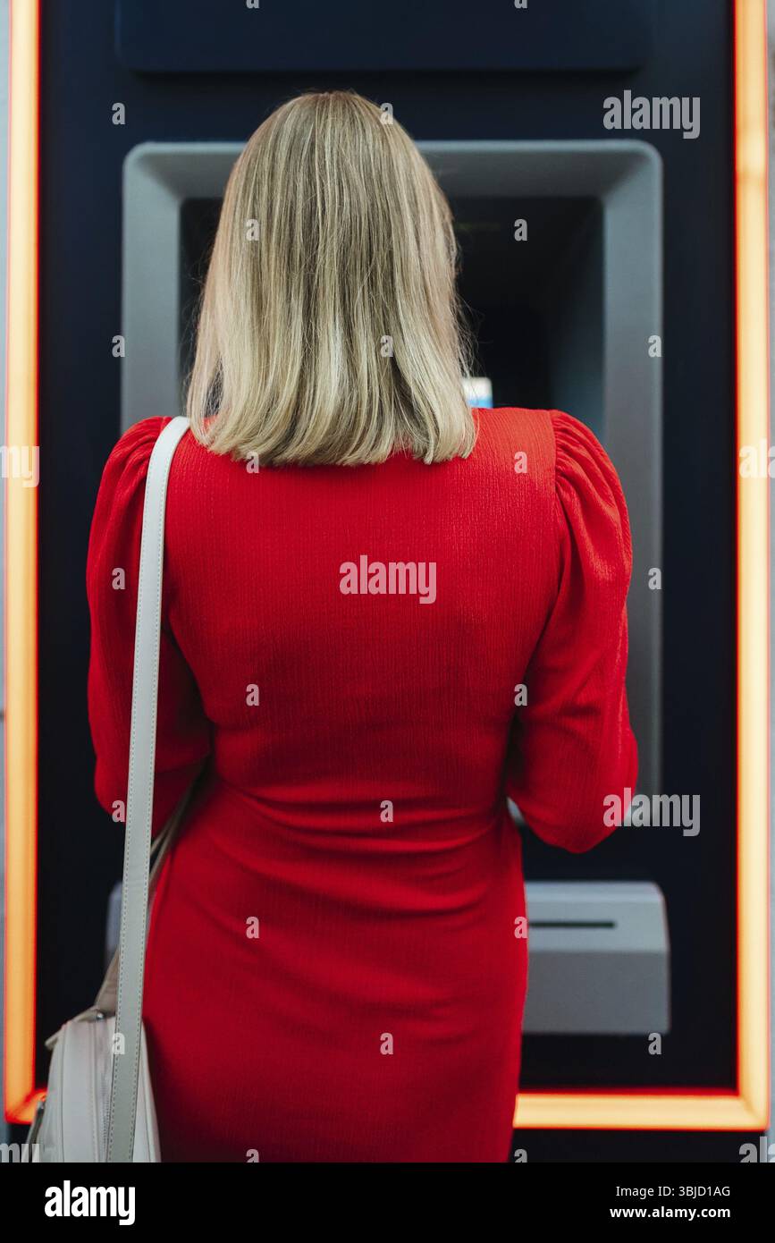 Donna che usa il bancomat per strada Foto Stock