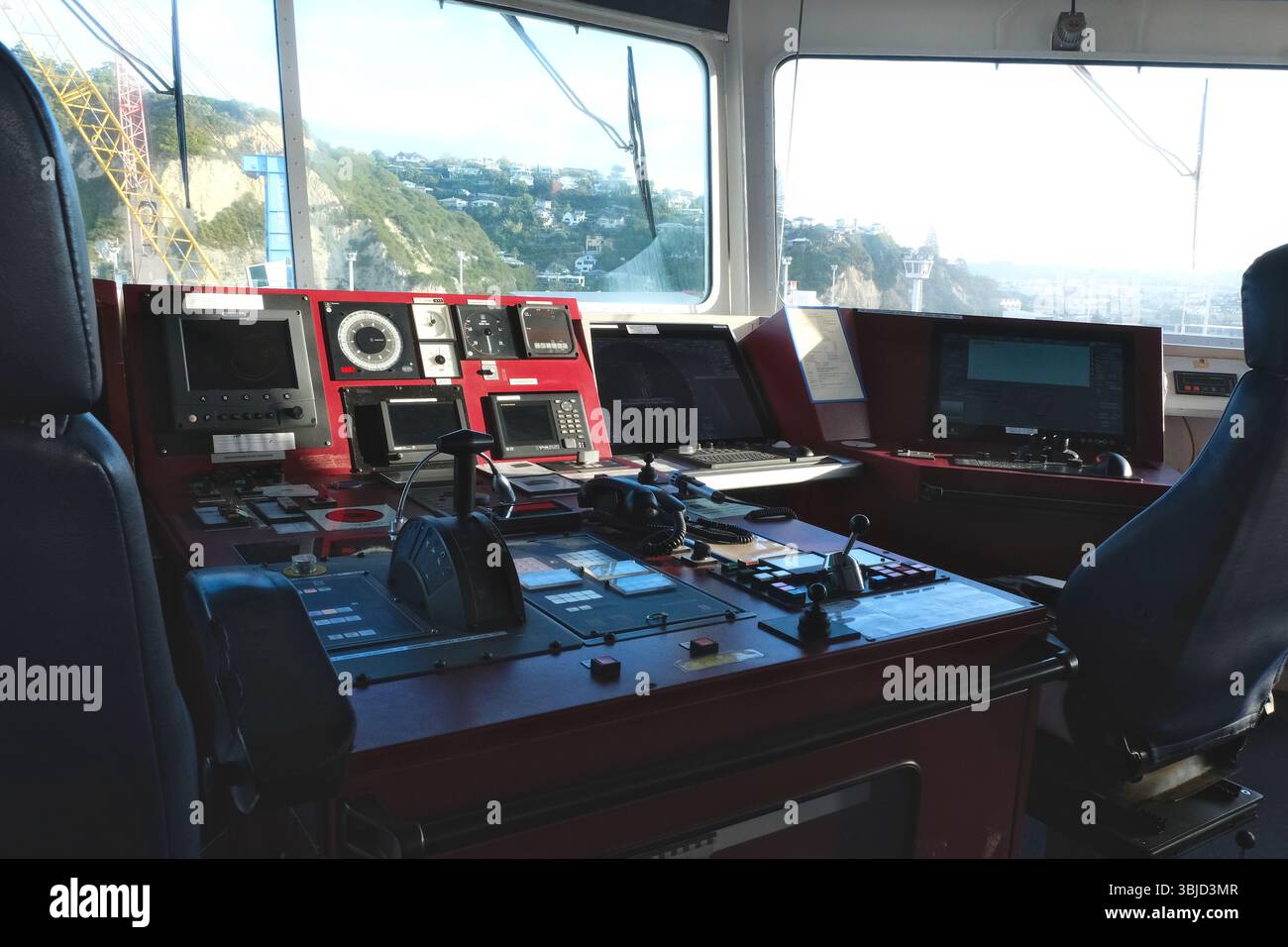 Moderna console di controllo Ship’s Bridge con attrezzature di navigazione e sedie per container con vista sul porto di Napier. Foto Stock