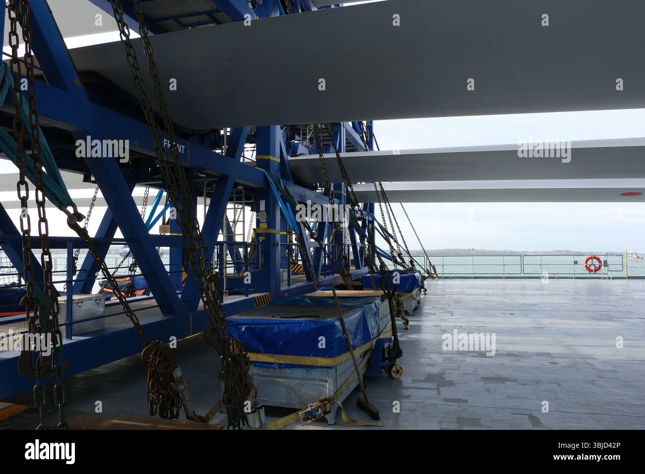Pale bianche di una turbina eolica caricate e fissate con cinghie, catene e tendicorda sulla nave portatrice di carichi pesanti che passa per il Mare del Nord. Foto Stock