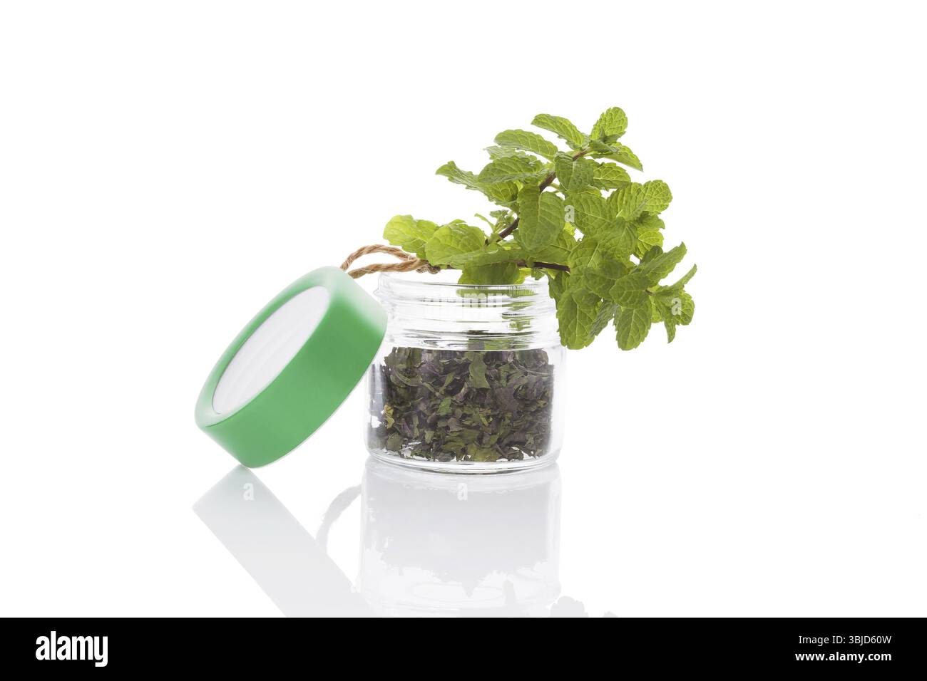 Guinzaglio fresco e spezie secche alla menta in vaso di vetro isolato su sfondo bianco. Erbe aromatiche salutari culinarie. Arte culinaria Foto Stock