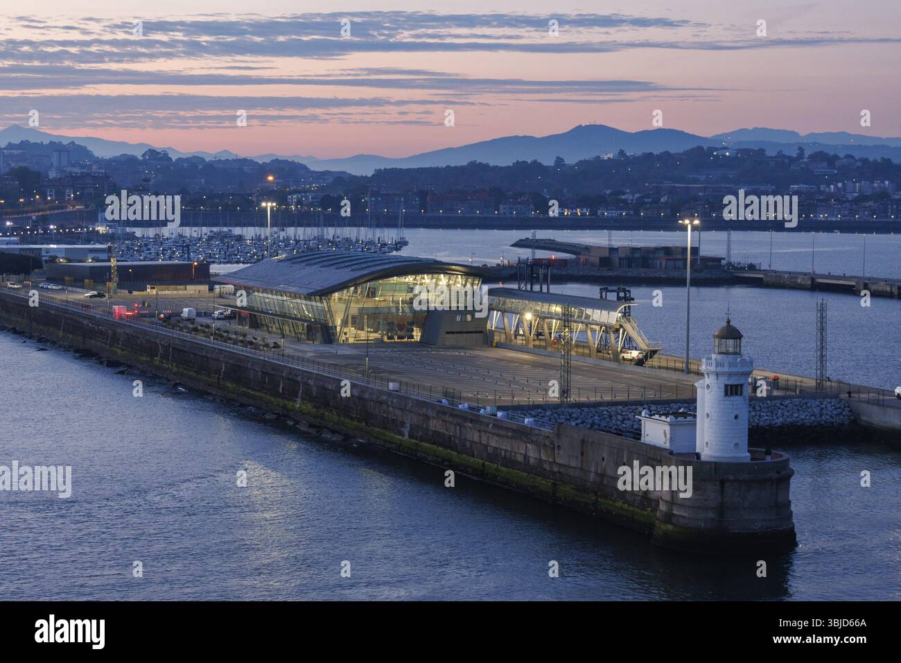 Un porto moderno con faro ed edifici illuminati al crepuscolo, Gexto, Paesi Baschi, Spagna, Europa Foto Stock