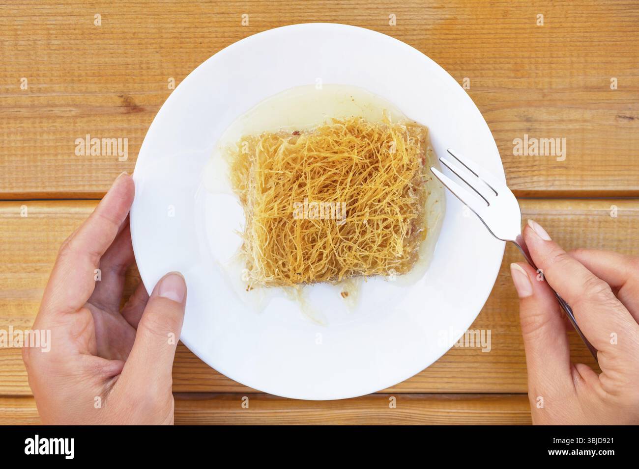 Vista dall'alto del kadaif dolce e croccante con miele su piatto bianco Foto Stock