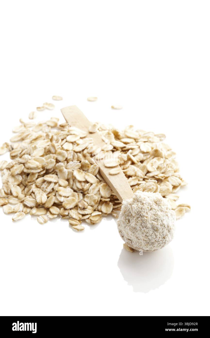 Mucchio di farina integrale d'avena in cucchiaio e fiocchi d'avena isolati su sfondo bianco Foto Stock
