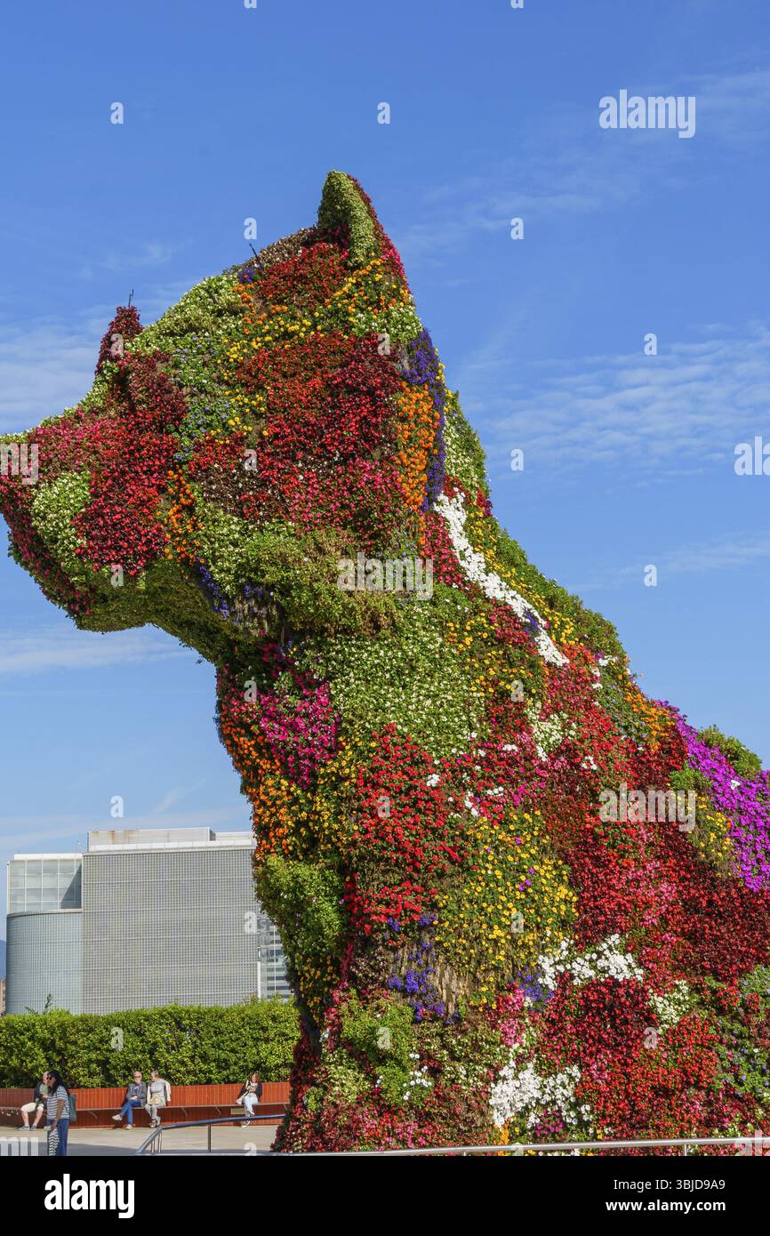 Gigantesca scultura per cani, realizzata interamente con fiori colorati, di fronte a un edificio moderno, Bilbao, Paesi Baschi, Spagna, Europa Foto Stock